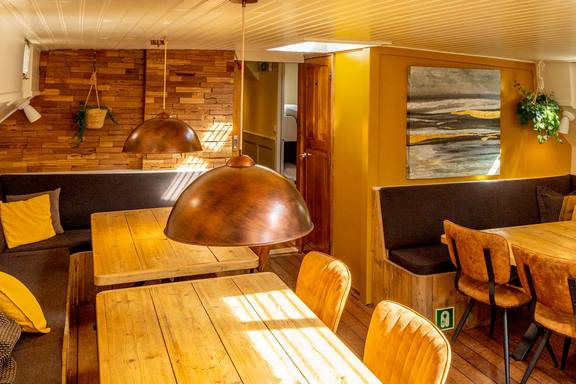 Sitzecke mit Holztisch und kupferner Hängelampe in der Avontuur