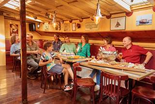 Gäste am Tisch im holzgetäfelten Salon des Klippers Anna