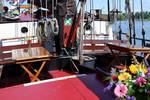 Sitzbereich mit Holztischen und Blumen an Deck der Avondrood