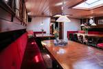 Salon der Avondrood mit Holzesstischen und roten Sitzbänken