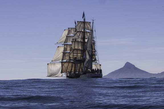 Bark Europa segelt entlang einer bergigen Küste