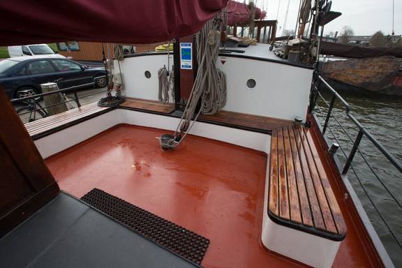 Holzbänke um den roten Sitzbereich an Deck der Boekanier