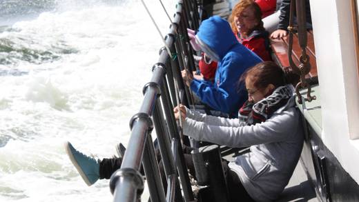 Schüler sitzen an Deck der Broedertrouw neben spritzendem Wasser