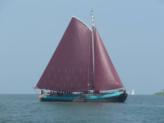 Dankbaarheid unter vollen braunen Segeln auf dem Wasser