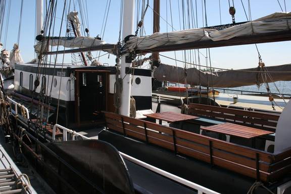 Holzbänke und Tische im Sitzbereich an Deck der Vrijheid