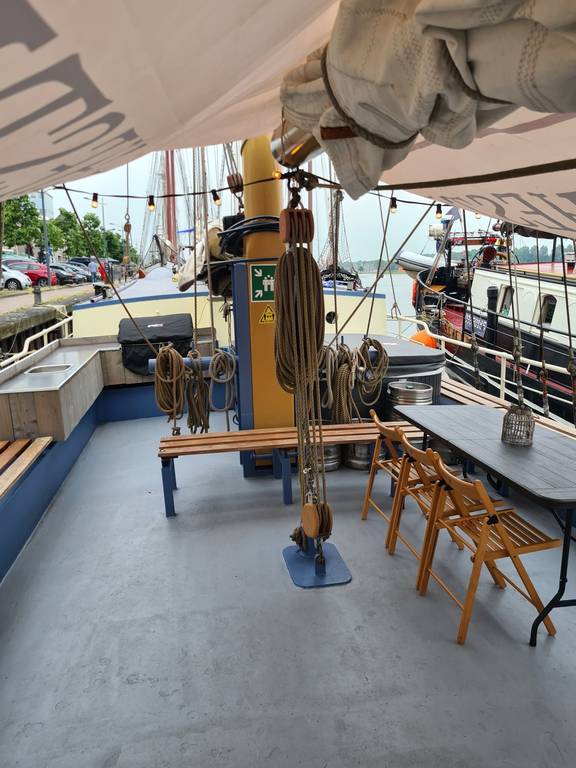 Sitzbereich der De Hester mit Bänken und einem Tisch unter einem Sonnensegel