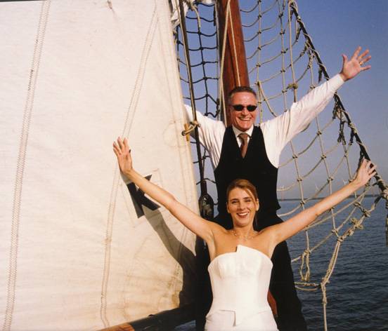 Brautpaar posiert mit ausgebreiteten Armen an den Segeln der Frisius van Adel