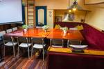 Salon der Gouwzee mit Holzesstischen und roten Sitzbänken