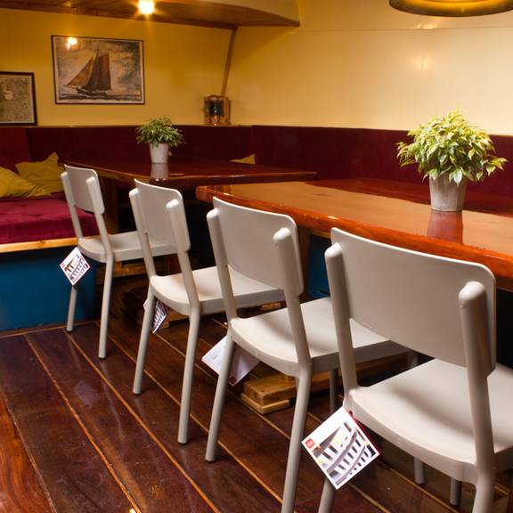 Salon der Gouwzee mit Holzesstischen und roten Sitzbänken