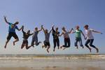 Eine Schülergruppe springt gemeinsam am Strand in die Luft