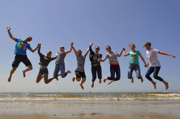 Eine Schülergruppe springt gemeinsam am Strand in die Luft