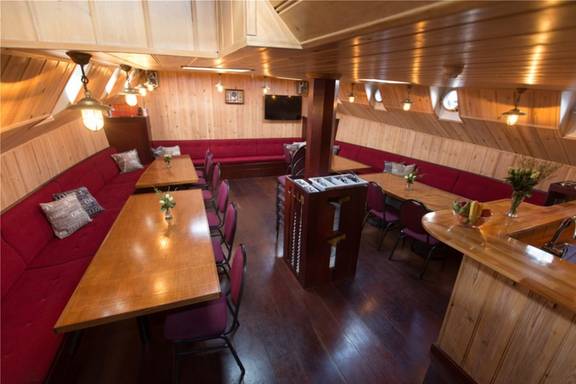 Salon der Grietje mit Holzesstischen und roten Sitzbänken