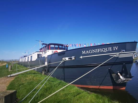 Das Passagierschiff Magnifique IV an einem grasbewachsenen Ufer festgemacht