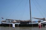 Tjalk Nieuwe Zorg im Watt trockengefallen mit Gästen neben dem Schiff