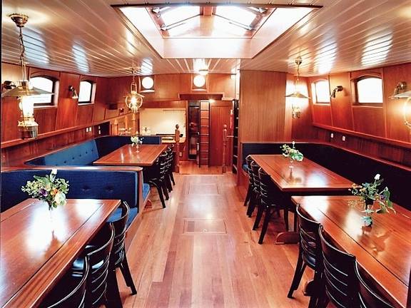 Salon der Poseidon mit Holzesstischen und blauen Sitzbänken