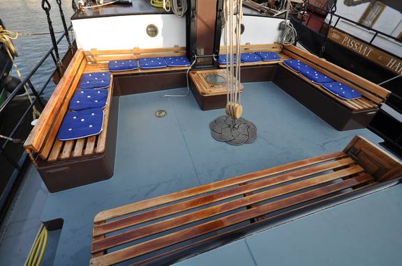 Holzbänke mit blauen Polstern im Sitzbereich an Deck der Poseidon