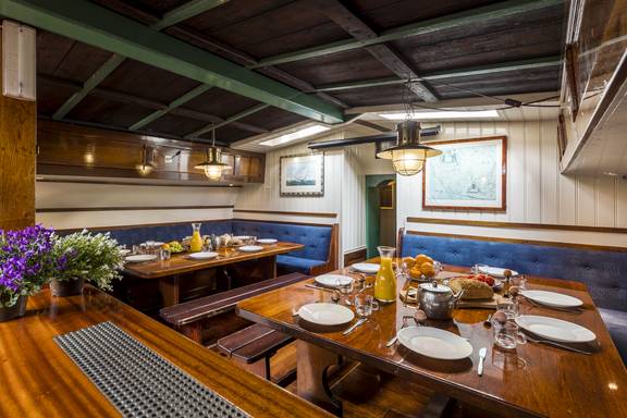 Holzverkleideter Salon der Spes Mea mit gedeckten Tischen und blauen Sitzbänken