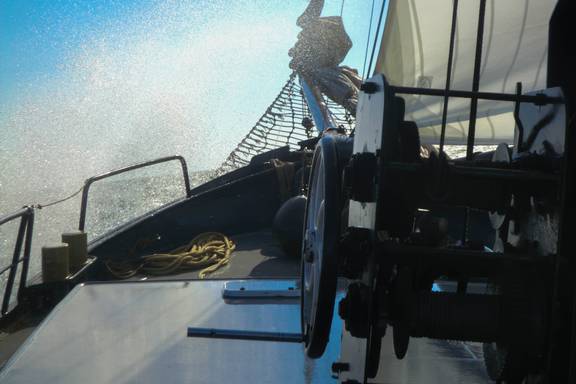 Wasser spritzt beim Segeln über das Vorschiff der Sybaris
