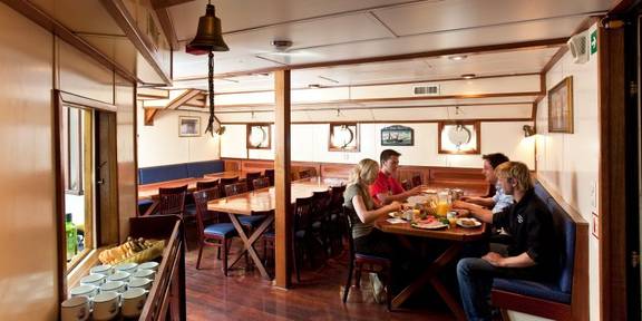 Gäste an den Esstischen im holzverkleideten Salon der Thalassa