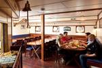 Gäste an den Esstischen im holzverkleideten Salon der Thalassa