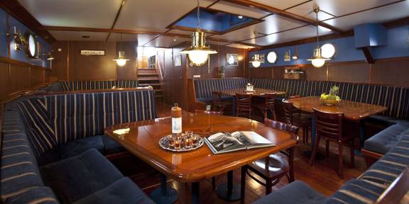 Salon der 't Wapen fan Fryslân mit Holzesstischen und dunklen Sitzbänken