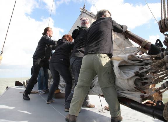 Gäste an Deck am Steuerrad eines Segelschiffs