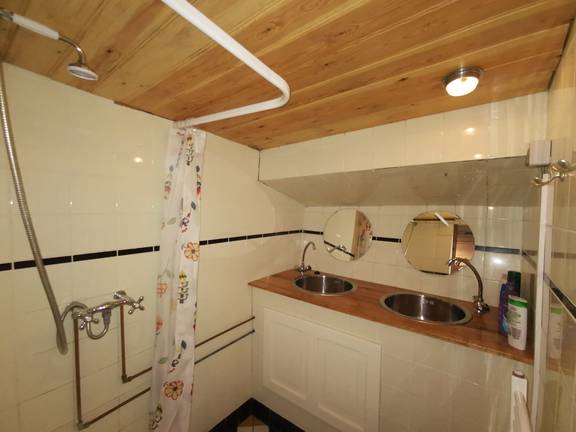 Badezimmer der De Lis mit Waschbecken und Dusche unter einer Holzdecke