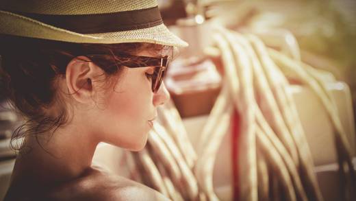 Frau mit Hut und Sonnenbrille entspannt in der Sonne
