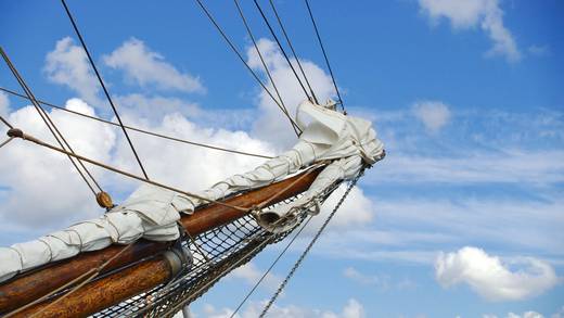 Blick hinauf an einem Mast mit weißen Segeln und Takelage