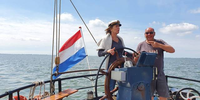 Zwei Gäste am Steuerrad eines Segelschiffs