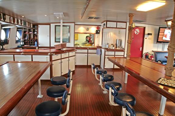 Salon der Eendracht mit langen Holztischen und fest montierten Hockern