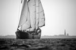 Mare fan Fryslân unter Segeln mit einer Hafenstadt im Hintergrund