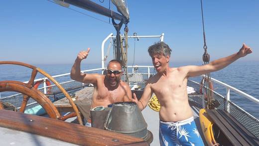 Freunde am Steuerrad bei einem Junggesellenabschied auf einem Segelschiff